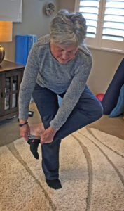 Joyce putting on sock while doing standing Figure 4 exercise move