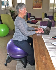 Joyce sitting with pelvis in neutral on ball chair while working on computer