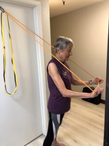 Joan using portable bands for chest presses