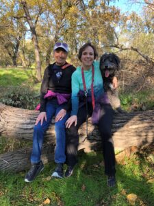 Joan sitting on a log with daughter, Cami, and Minnie along the American River in Sacramentoiver witSottog Daught
