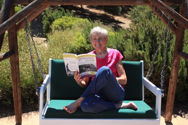 Joan on Swing reading Dynamic Aging Book